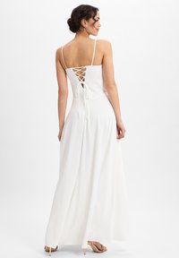 Weißes Maxikleid mit einer taillierten Oberseite, verstellbaren Spaghetti-Trägern und einer gekreuzten Schnürung im Rücken. Weicher, fließender Stoff.