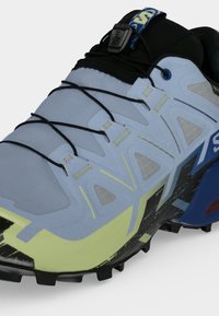 Παπούτσι για trail running σε μπλε, κίτρινο και μαύρο χρώμα, με σύστημα γρήγορου κορδονιού και ανθεκτική σόλα για πρόσφυση εκτός δρόμου.