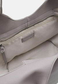 Binnenkant van een grijze leren draagtas met een ritsvak en een textuurrijke voering. De tas is gemaakt van zachte, gladde materialen en heeft een minimalistisch ontwerp.