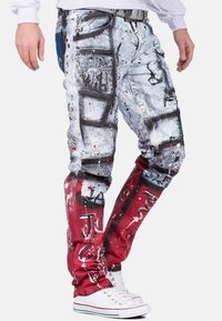 Pantaloni cargo con colori grigio e rosso arricchiti da design in stile spray paint. Tessuto rovinato, numerose tasche e una vestibilità slim.