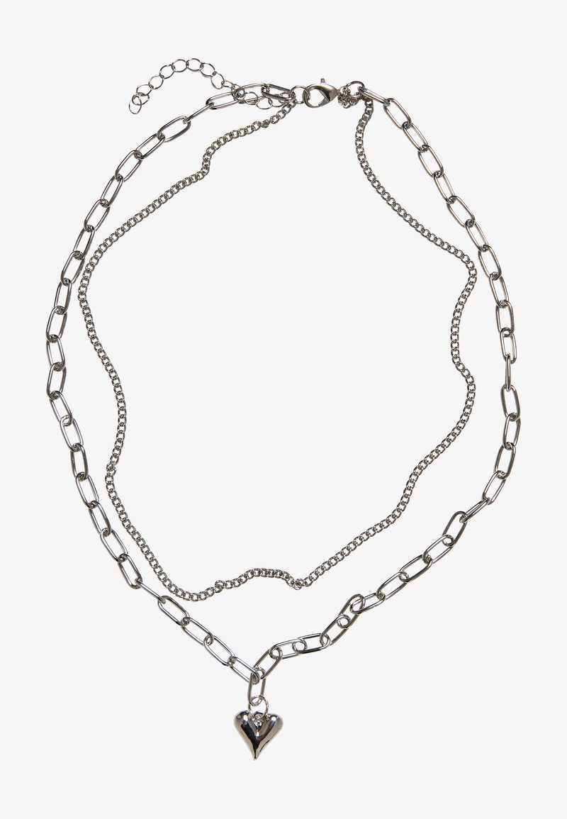 Collier en argent avec des styles de maillons variés, y compris une petite chaîne et de plus grands maillons ovales, avec un pendentif en forme de cœur brillant.