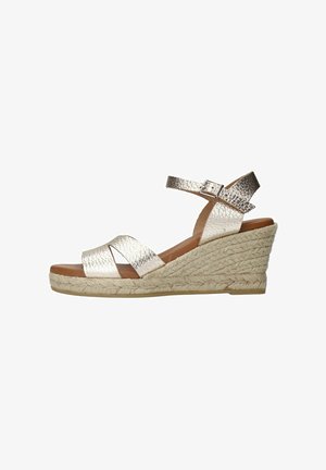 Wedge sandal with a metallic silver upper and crisscross straps. Natural jute rope wedge and a padded footbed for comfort. Adjustable ankle strap.