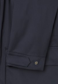 Chaqueta cortavientos de color navy en primer plano, con un tejido suave, cierre de botones a presión oculto, y un diseño elegante sin patrones visibles.