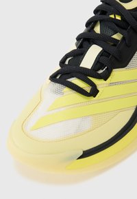 Lime yellow athletic shoe with mesh and synthetic upper, black laces, and distinctive yellow stripes. Transparent rubber sole for grip.