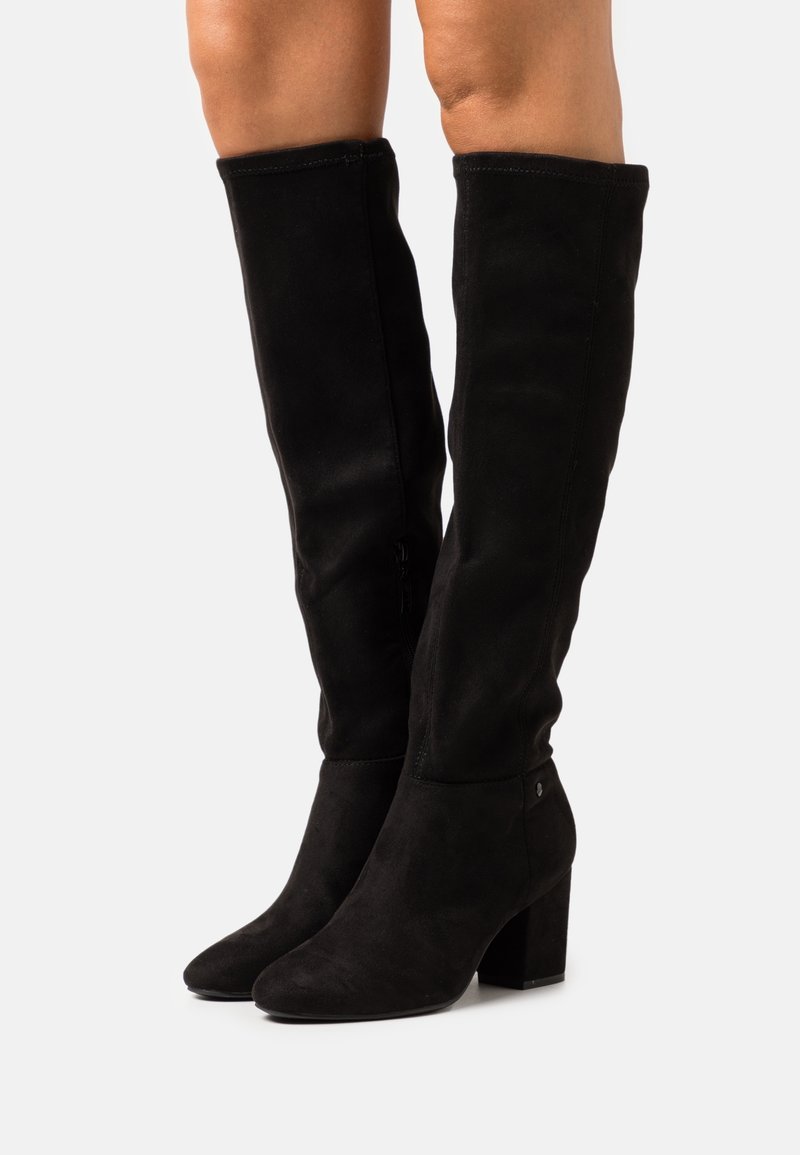 Botas negras por encima de la rodilla de suave ante, con punta afilada y tacón grueso. Textura suave con acentos mínimos.