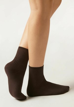 Braune, gerippte Knöchelsocken aus weichem Material. Das Design verfügt über eine verstärkte Ferse und Spitze mit regulärer Bündchenhöhe.