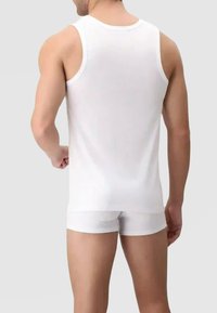 Top bianco senza maniche con una texture liscia e scollatura rotonda, abbinato a pantaloni corti bianchi attillati, visto da dietro.