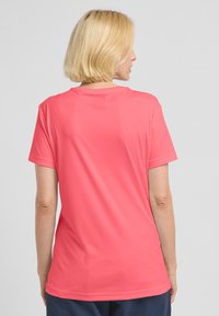 T-shirt corallo a maniche corte realizzato in tessuto leggero e morbido, con scollatura rotonda e taglio dritto con cuciture minime.