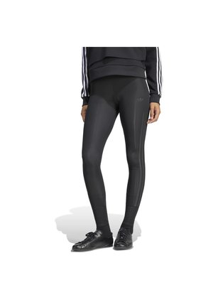 Oseba nosi črne Adidas legice s tremi črtami na strani, črne superge in črno majico s kapuco z belimi črtami na rokavih.