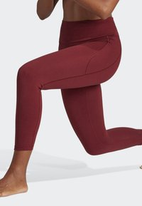 Bordowe legginsy treningowe z wysokim stanem, gładką fakturą i kontrastującymi szwami bocznymi. Lekki i dopasowany krój, idealny do aktywności.