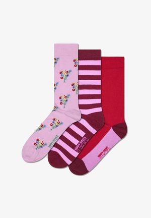 Three pairs of socks in pink, red, and burgundy. The pink sock features floral patterns; striped burgundy and pink; solid red. Cotton blend material.