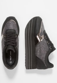 Mustat lenkkarit, joissa on kiiltävät hopeiset yksityiskohdat, teksturoitu päällinen, paksu musta pohja ja kuusi silmukkaa nauhoille, jotka esittelevät modernia urheilullista muotoilua.