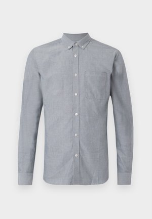 Camisa de botón de manga larga y color azul claro, hecha de tejido tejido. Presenta un solo bolsillo en el pecho y un cuello con botones. Textura similar a la satén.