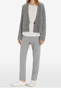 Šedý pletený kardigan, bílá halenka a světle šedé kalhoty na míru. Dokončeno bílými teniskami s třemi horizontálními pruhy.