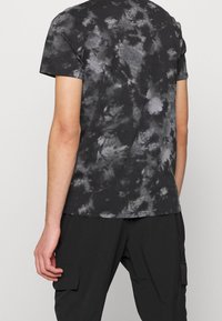 Svart och grå tie-dye T-shirt i bomull med rund halsringning och korta ärmar, med en avslappnad passform och mjuk textur.