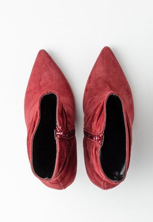 Czerwone zamszowe botki z ostrymi noskami, bocznymi zamkami i gładkim czarnym wnętrzem. Płaska podeszwa, z czystą, minimalistyczną sylwetką.