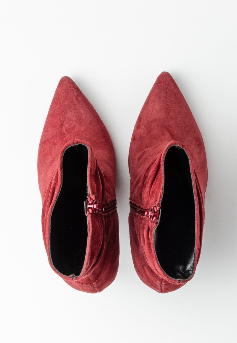 Bottines en daim rouge à bouts pointus, zips latéraux, et intérieur noir lisse. Semelle plate, silhouette épurée et minimaliste.