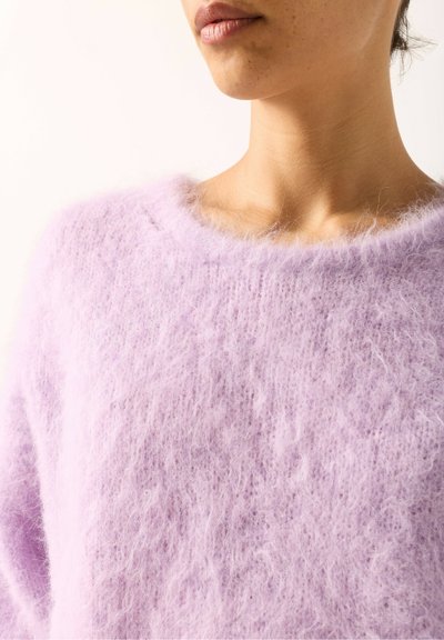 Pull en mohair lavande à encolure ronde, texture douce et apparence duveteuse, mettant en valeur un tricot lâche et des fibres délicates.