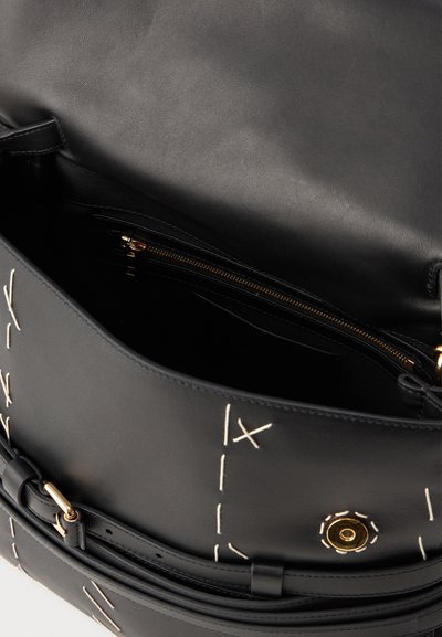 Borsa in pelle nera con dettagli cuciti a contrasto, dotata di apertura superiore, hardware dorato e una tasca con zip interna per l'organizzazione.