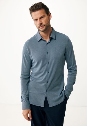 Camisa de manga larga abotonada en tejido azul jaspeado, con un cuello clásico y una tapeta en el frente, botones oscuros y un ajuste relajado.