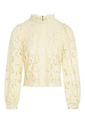 Blouse en dentelle crème à manches longues avec col montant, bords festonnés, motifs floraux découpés complexes et fermeture éclair au dos.