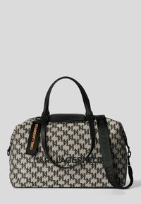 Sac en tissu noir et beige avec un motif de logo répétitif, poignées doubles, une bandoulière amovible et un accent noir lisse sur le dessus.