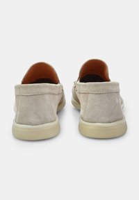 Pantofi slip-on bej din suede, cu vârf rotund și talpă joasă din cauciuc. Detalii de cusătură de-a lungul marginilor și interior căptușit.