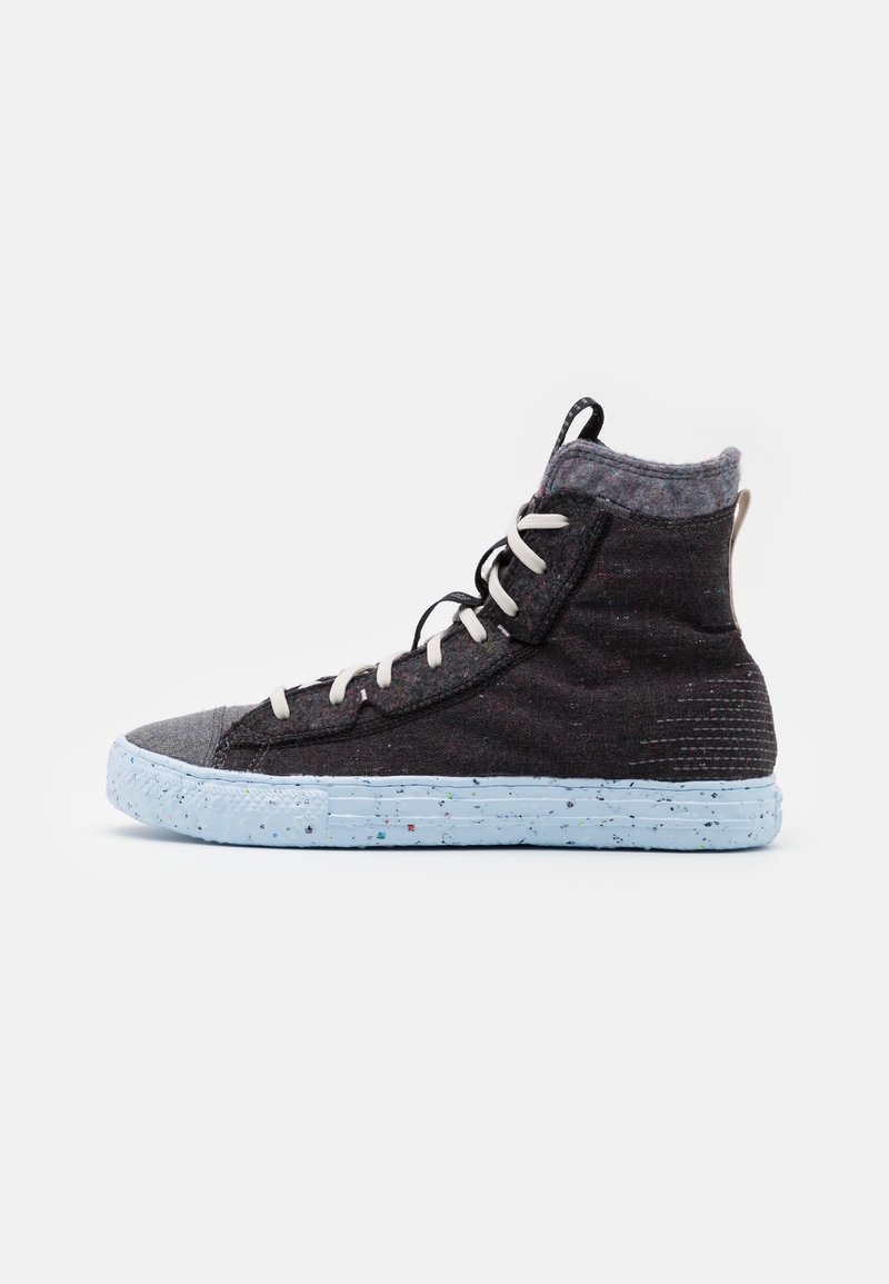 Sneaker montante en matériau gris foncé avec une semelle en caoutchouc bleu clair à motifs, des lacets blancs et un col de cheville texturé.