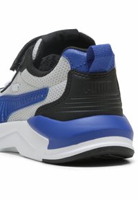 Sneaker sportivo con rete blu, nera, bianca e grigia, dotato di una fascia con velcro e suola texturizzata per trazione e supporto.