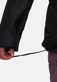 Schwarze wasserdichte Jacke mit verstellbarem Bündchen, die einen gezogenen Kordelzug aufweist. Das Material wirkt glatt mit einer matten Oberfläche.