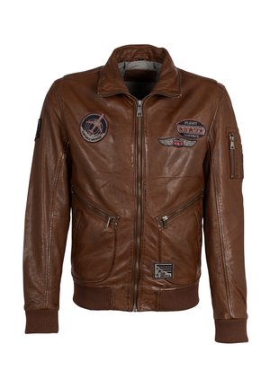 Veste en cuir marron avec fermeture éclair à l'avant, deux poches latérales et poignets côtelés. Décorée de plusieurs écussons, dont des insignias de vol et nationaux.