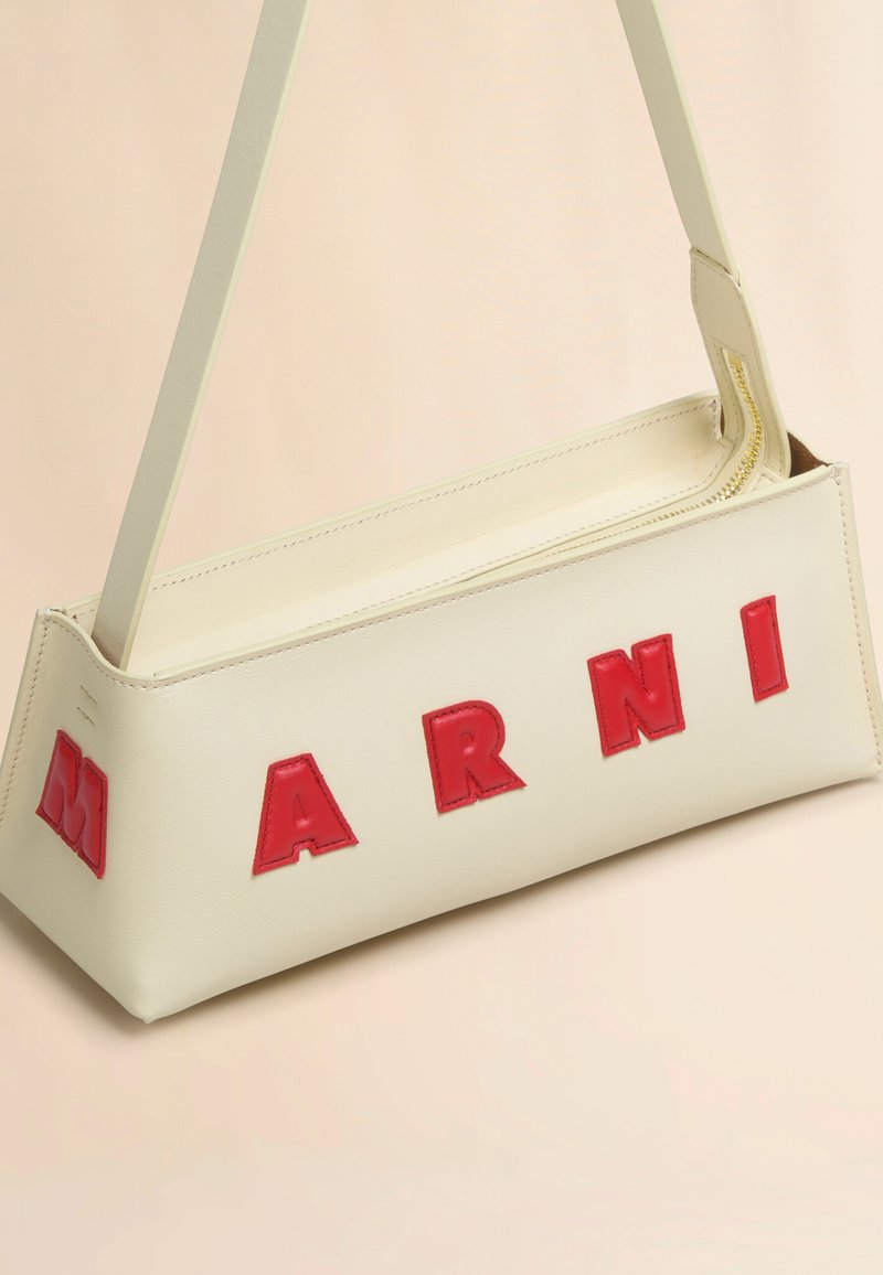 Borsa a spalla in pelle crema con audaci lettere rosse che spellano "MARNI," dalla forma rettangolare e strutturata con chiusura a zip.