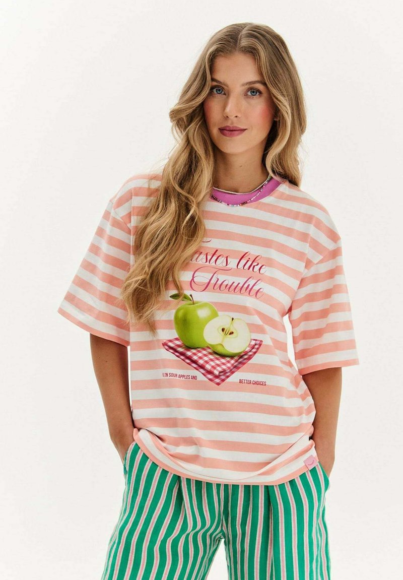 Pruhované tričko v ružovej a bielej farbe s grafikou zelených jablk na červenej kockovanej šablóne. Voľný strih, krátke rukávy, bavlnený materiál.