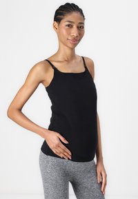 Top senza maniche nero con scollatura a barchetta, realizzato in tessuto morbido. Presenta spalline regolabili e una vestibilità comoda e rilassata.