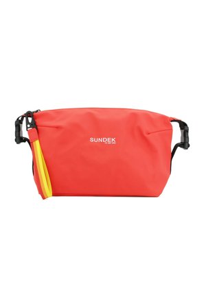 Busta Sundek rossa con cerniera, con clip neri in plastica ai lati e cinturino da polso a righe giallo-arancio attaccato al clip sinistro.