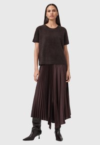 Ciemnobrązowy sweter z krótkim rękawem, uszyty z miękkiego materiału, w połączeniu z plisowaną długą spódnicą w bogatym burgundowym odcieniu, uzupełniony czarnymi botkami do kolan.