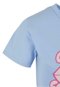 Light blue cotton T-shirt featuring a crew neckline and short sleeves. Notable pink graphic design on the front with rounded shapes.
