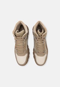 Světlé hnědé a krémové vysoké tenisky s texturovaným povrchem, béžovými tkaničkami a polstrovaným límcem. Obsahují detaily loga a gumovou podrážku.