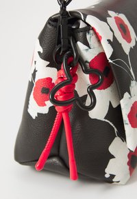 Borsa in pelle nera con design floreale. Presenta una tracolla con un accento rosso e una chiusura nera. Texture liscia con una forma strutturata.