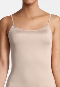 Nude camisole with thin straps, made of smooth, stretchy fabric. Features a scoop neckline and a fitted silhouette. Simple design.