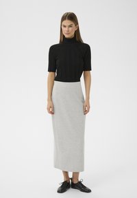 Schwarzes, geripptes Rollkragenoberteil, grauer Midirock aus weichem Stoff, kombiniert mit schwarzen Schnürschuhen. Einfaches, figurbetontes Design.