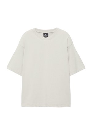 Lyse beige, oversized T-shirt med korte ærmer og rund halsudskæring samt synligt mærke indeni kraven på en hvid baggrund.
