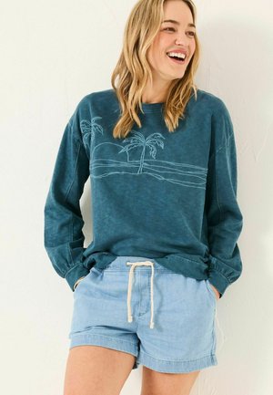 Tealfarbener Langarm-Sweatshirt mit Palmbaum-Stickerei, kombiniert mit hellblauen Shorts mit Kordelzug. Weicher, lässiger Stoff, entspannter Schnitt.