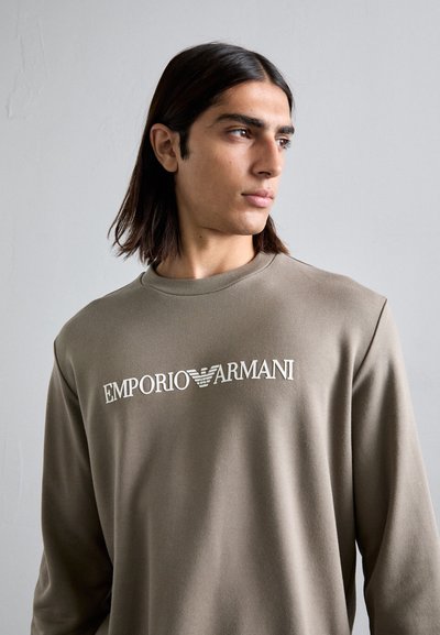 Olajzöld pulóver puha anyagból, kerek nyakkivágással és fehér "EMPORIO ARMANI" logóval a mellkasán.