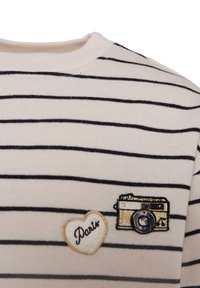Gestreepte katoenen trui in crème en zwart, met een gouden camera en een hartvormige "Paris" patch op de linkerkant van de borst.