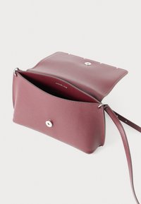 Piccola borsa a tracolla in pelle bordeaux con finitura texturizzata, chiusura a scatto magnetico e tracolla rimovibile. Interno foderato in colore coordinato.
