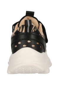 Baskets noires avec un motif zèbre, un col rembourré, des accents dorés et une semelle en caoutchouc blanc avec une texture antidérapante.
