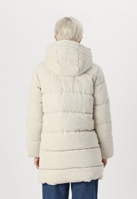 Lys beige kordfløjl pufferjakke med hætte, der har et kviltet design og en afslappet pasform. Ærmerne er let samlet for komfort.