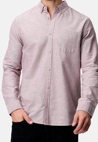 Chemise à manches longues avec col en tissu texturé rose clair, dotée d'une poche poitrine et d'une fermeture à boutons à l'avant avec des boutons assortis.