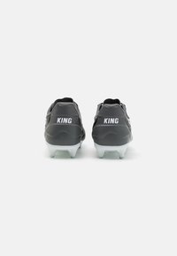 Scarpe da calcio nere con tomaia texturizzata, marchio "KING" bianco e tacchetti traslucidi. Vista posteriore che mostra contorni eleganti e un design minimale.